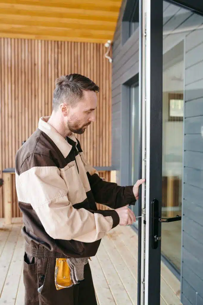 young-repairman-fixing-lock-in-large-transparent-door-682x1024